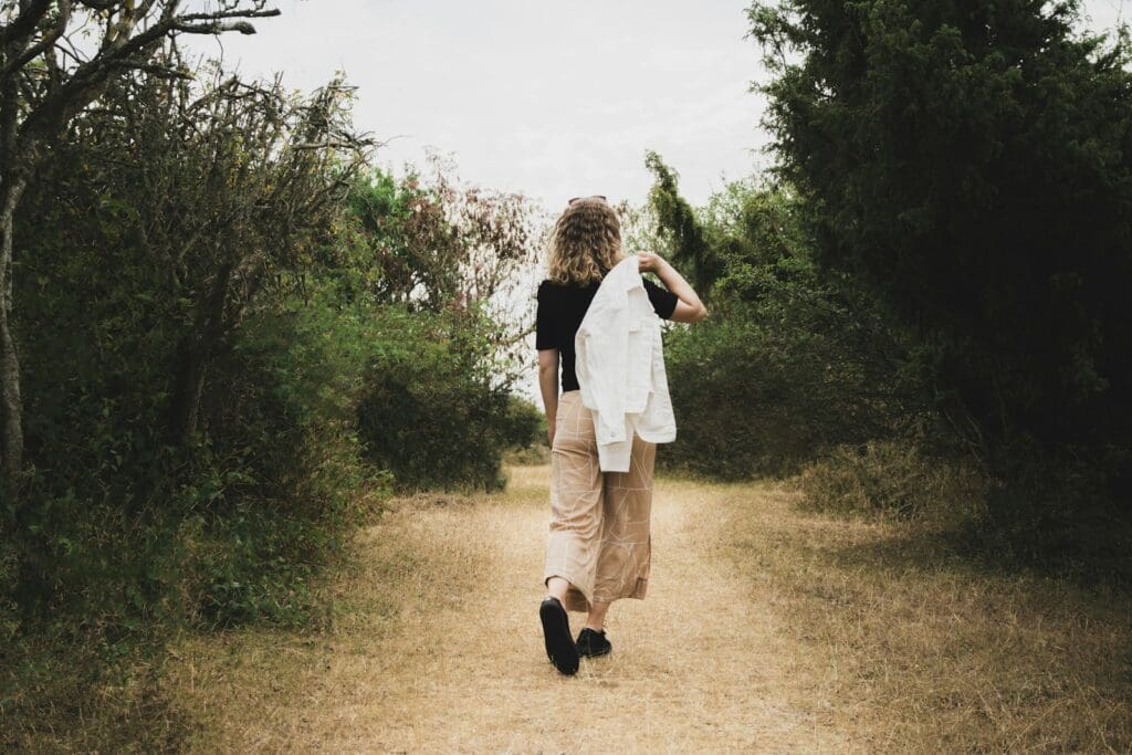 woman in white dress shirt and black pants standing on green grass field during daytime